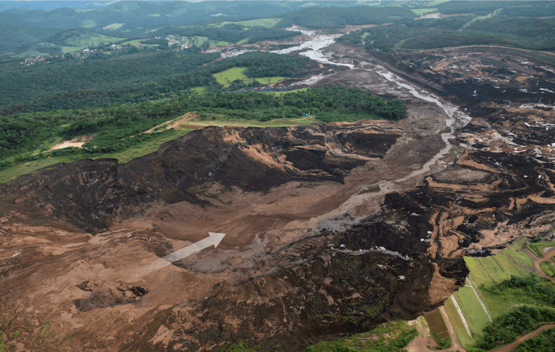 Photograph depicting the aftermath of the failure of Brumadinho Dam. An arrow indicates the breach.