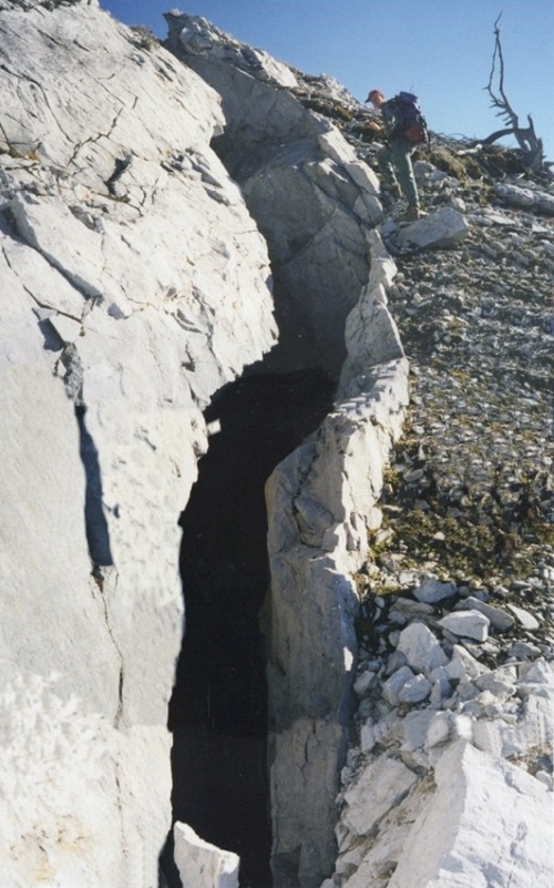 Color photograph. The vertical crevasse is roughly 5 researchers tall and 3 researchers wide.